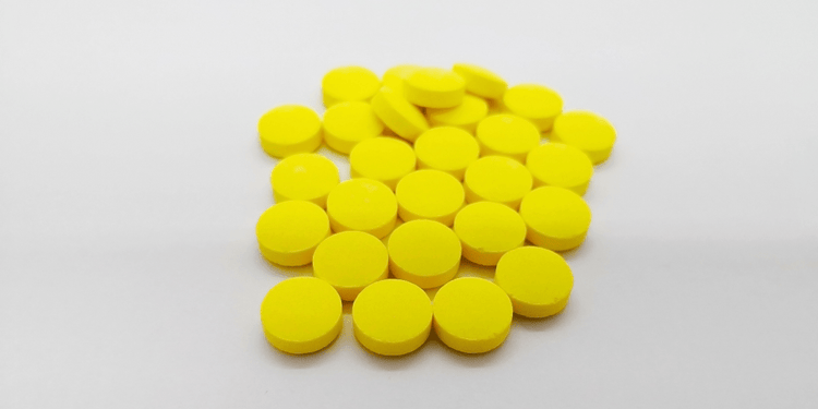 A large number of yellow metronidazole pills on a white table.