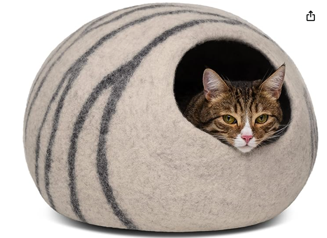 a cat poking its head out of a cave bed