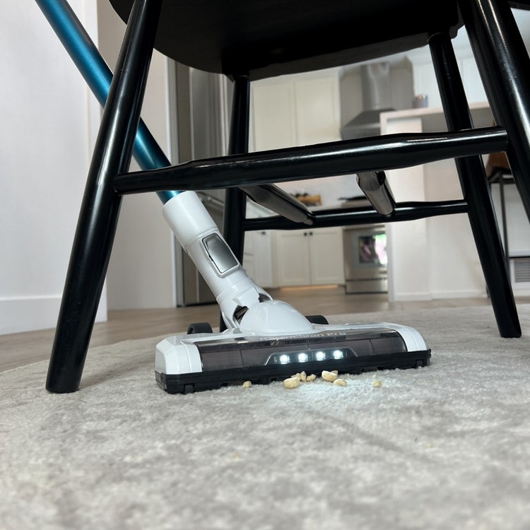 A vacuum cleaner under a chair Description automatically generated